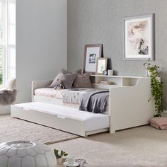 a white day bed sitting in a bedroom next to a window with pictures on the wall