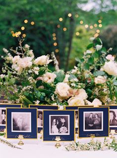 a table topped with pictures and flowers on top of a white cloth covered tablecloth