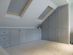 an attic bedroom with gray cabinets and white carpeted flooring on top of the walls