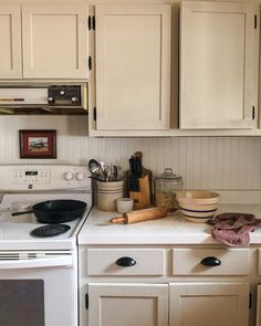 a white stove top oven sitting inside of a kitchen next to wooden cupboards and drawers