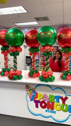 a woman standing behind a counter with balloons on it