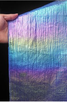 a hand holding up a piece of paper with an iridescent pattern on it