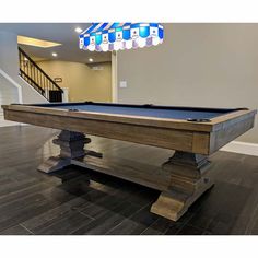 a pool table in the middle of a living room with stairs and chandelier