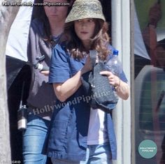 two women walking out of a building with one holding a water bottle and the other looking at her cell phone