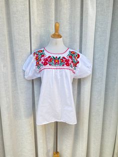 "Beautiful Vintage white flowy Crewneck top with bubble short sleeves and red floral embroidery at top. Red stitching along neckline and two red flowers on back. Gorgeous top, very lightweight and airy, bright colors! Great condition! No makers mark or size tag so please see measurements below for proper sizing and fit. Measurements (flat): Shoulder to shoulder: 15\" Armpit to armpit: 19.5\" Shoulder to hem length: 27\" Bottom width: 22\"" White Embroidered Short Sleeve Top, White Puff Sleeve Top With Floral Embroidery, Red Summer Top With Embroidered Neckline, Summer Red Tops With Embroidered Neckline, White Floral Embroidery Short Sleeve Top, White Floral Embroidered Short Sleeve Top, Casual Red Blouse With Floral Embroidery, Summer Red Top With Embroidered Neckline, Red Top With Embroidered Neckline For Summer