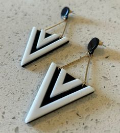 This is a fun pair of black and white acrylic drop earrings from the 1990's. The earrings start with a black flat small round round dot top. The earrings then have 2 gold bars hanging below, which are connected to a large black and white triangle acrylic triangle. The earrings are in new old stock condition. The earrings measure 3 1/2" long and 1 1/4" wide. A fantastic gift for yourself or someone you love! Black Retro Earrings, Retro White Dangle Earrings, Retro White Drop Earrings, Diy Soda, Round Round, Black And White Earrings, Gold Bars, White Earrings, Gold Bar