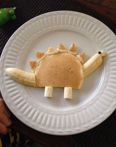 a white plate topped with banana slices and a cut out of a dinosaur face on it