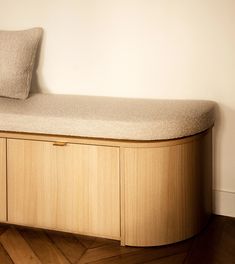 a wooden bench sitting on top of a hard wood floor next to a white wall