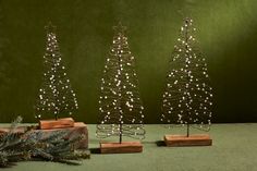 three small christmas trees sitting next to each other on top of a green tablecloth