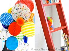 there are many colorful balloons hanging on the wall and in front of a red ladder