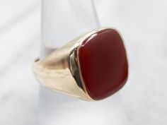 This beautiful Mid-Century mounting combines sleek styling and intense color. This beautifully styled ring with a warm rich Carnelian center. Carnelian is the reddish-orange version of Chalcedony and can either be uniformly colored or have visible bands through the stone.Material: 10K Yellow GoldGem: CarnelianGem Measurements: 13.9 x 16.2 mm, Rectangle Cushion Cut Size of Ring: 9.50Marks: "JASON 10K" Stamped on the inside band Formal Carnelian Signet Ring With Polished Finish, Classic Carnelian Signet Ring With Polished Finish, Classic Carnelian Signet Ring For Formal Occasions, Classic Carnelian Signet Ring For Formal Events, Formal Red Carnelian Signet Ring, Classic Carnelian Rings With Polished Finish, Classic Orange Rings With Polished Finish, Red Carnelian Signet Ring With Polished Finish, Red Carnelian Ring With Polished Finish