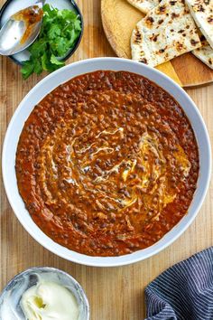 a white bowl filled with baked beans next to pita bread