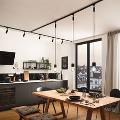 an open kitchen and dining area with wooden flooring, black appliances and white walls