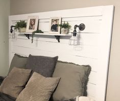 a bed that has some pictures on the wall above it and two hanging planters