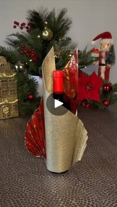 a wine bottle wrapped in gold paper next to a christmas tree and other holiday decorations