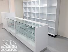 an empty room with white shelving and glass display cases on the wall, in front of a large window