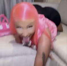 a woman with pink hair laying on top of a couch