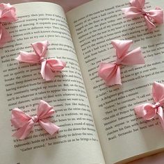 four pink bows on top of an open book