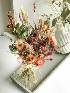 a vase filled with lots of flowers on top of a white counter next to a mirror