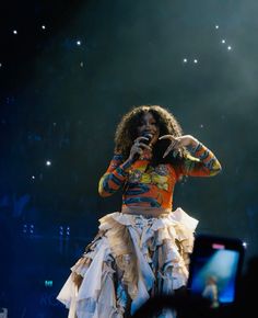 a woman in a colorful top and skirt on stage