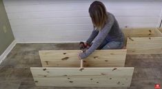 a woman kneeling on the floor working on some wooden boxes with screwdrivers in it