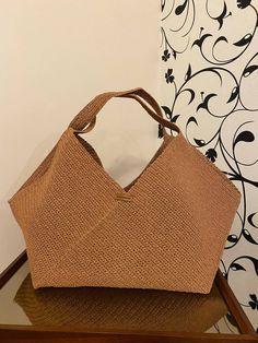 a brown purse sitting on top of a wooden table next to a black and white wall