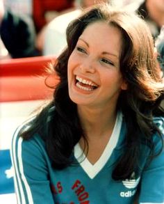 a smiling woman sitting on top of a bench in front of a group of people