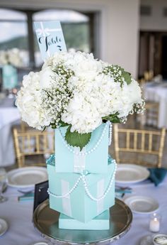 there is a blue box with white flowers in it on top of a silver plate