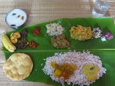 a banana leaf with various foods on it and a glass of water next to it