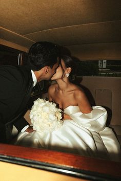 a bride and groom kissing in the back of a car