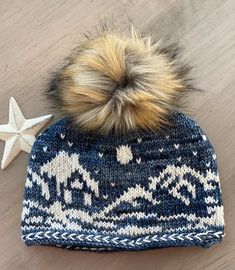 a knitted hat with a star on the side and a pom - pom