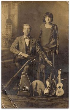 an old black and white photo of a man and woman posing with guitars in front of them