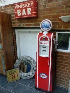 an old fashioned red and white gas pump in front of a brick building with signs on it