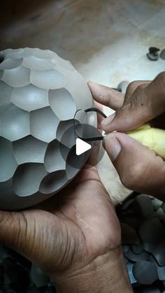 a person is working on something in the shape of a ball with an opening tool