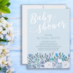 baby shower card with flowers and greenery on blue wooden background, flat lay style