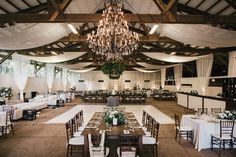 an indoor wedding reception with chandeliers and tables set up for the guests to eat