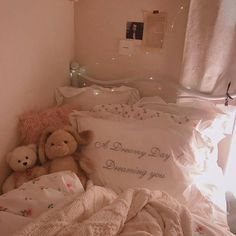 two teddy bears sitting on top of a bed next to pillows and blankets in a room