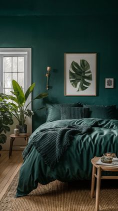 a bedroom with dark green walls and wooden flooring, large plant in the corner