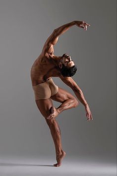 a man with no shirt on is doing a dance move in front of a gray background