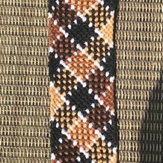 an orange, black and white knitted tie laying on top of a wicker mat