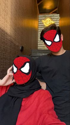 two people wearing spider man masks on their faces