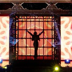 a person standing on top of a stage with their arms outstretched in front of them