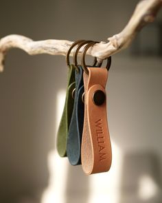 three leather keychains hanging from a tree branch with the name mia on them