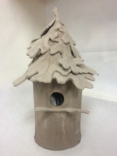 a birdhouse with a snowy roof and snow on the roof is made out of clay