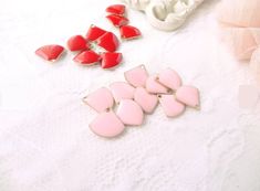 some pink and red earrings are laying on a white surface next to a pair of shoes