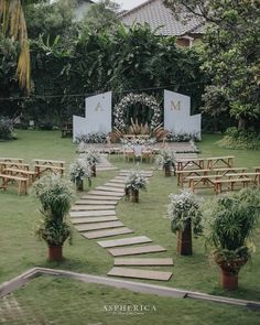 an outdoor ceremony setup with wooden benches and flowers on the grass, surrounded by greenery