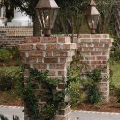 two lamps on top of brick pillars with ivy growing around them