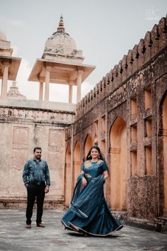 a man and woman standing in front of an old building