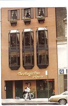 a person riding a bike in front of a tall building with windows on the side