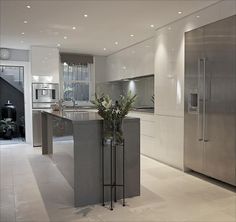 a modern kitchen with stainless steel appliances and marble counter tops, along with an island in the middle